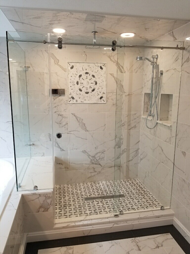 Close up view of marble tile shower with sliding glass shower door installed by Great Lakes Glass