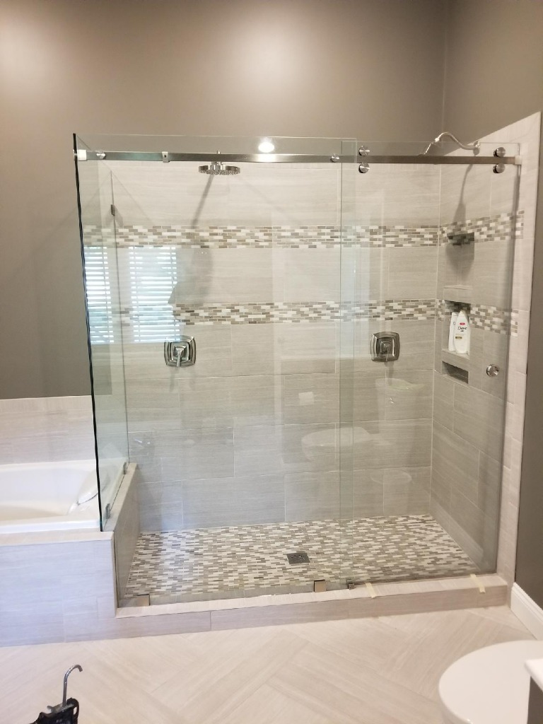 Frameless sliding glass shower enclosure with barn door track installed by Great Lakes Glass