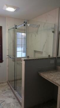 Frameless glass shower with sliding door and half glass wall installed by Great Lakes Glass in Cleveland, Ohio